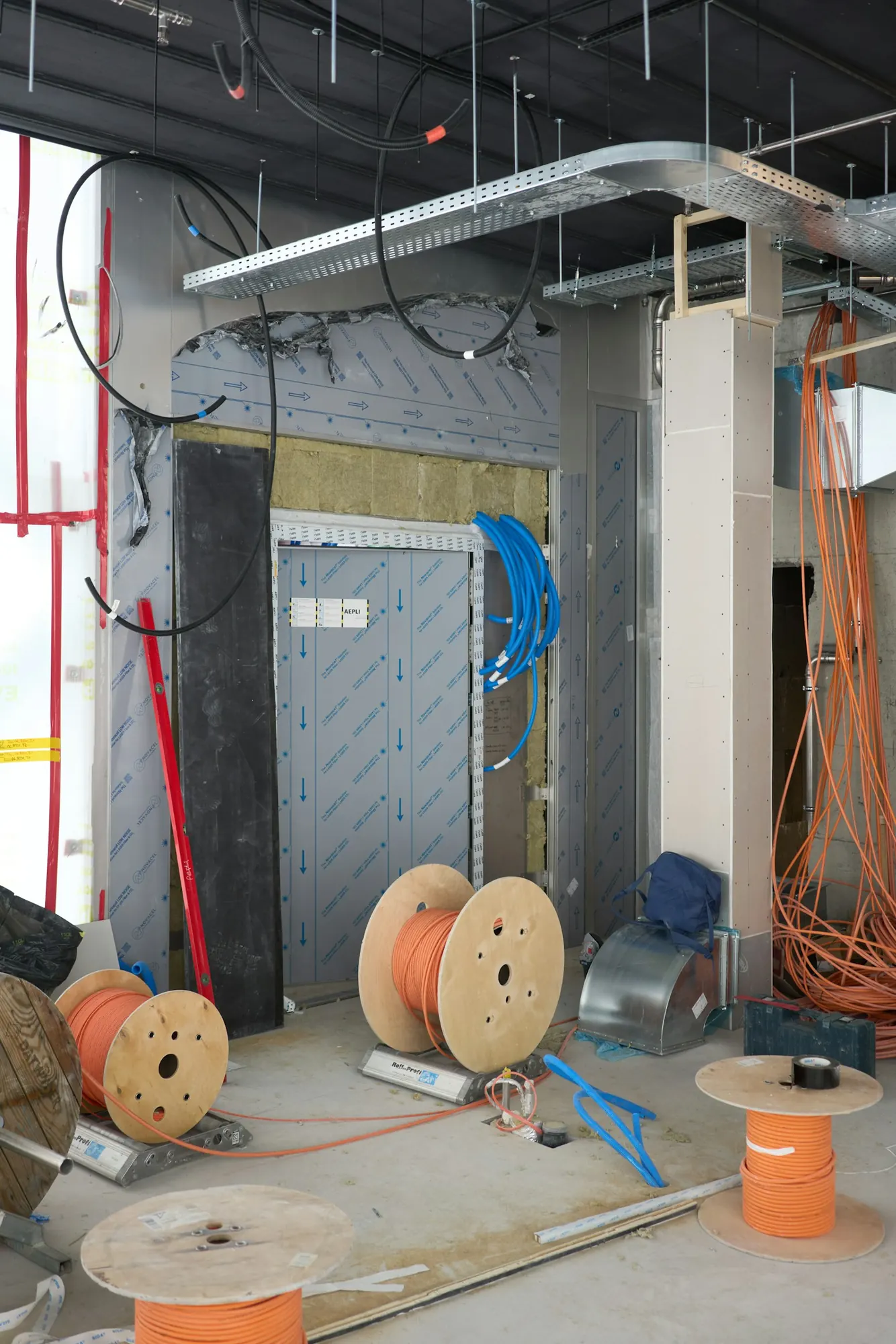 Rohbau mit Kabeltrasse an der Decke und Kabeltrommeln auf dem Boden